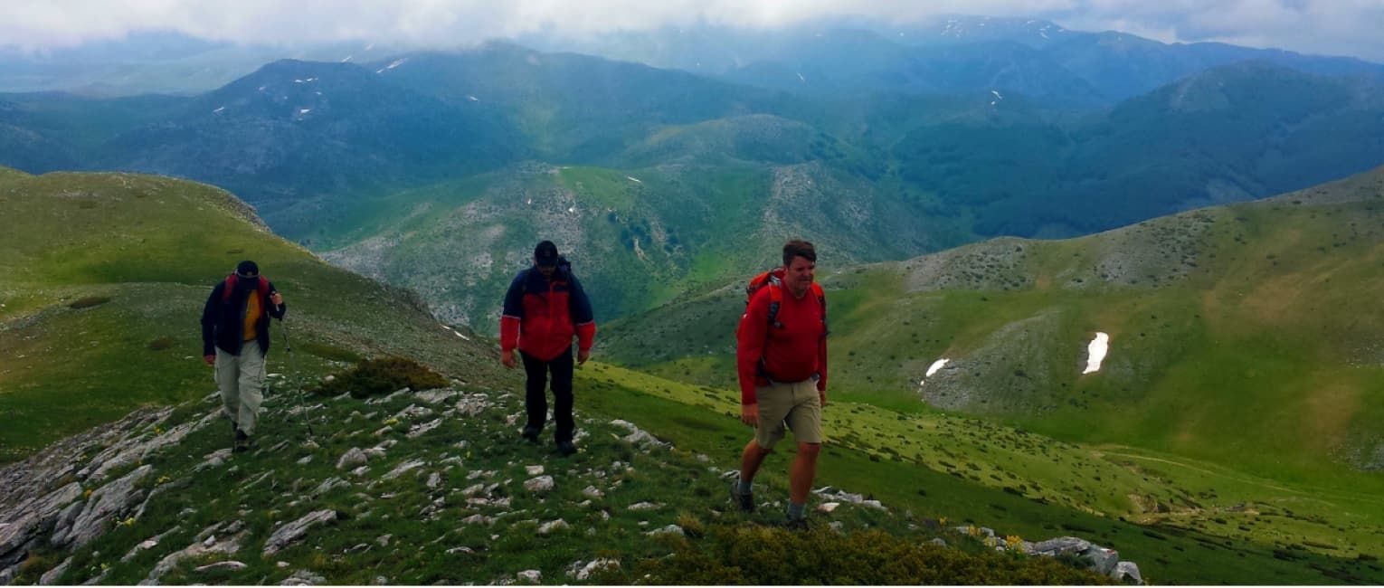 a group of 3 hikers making their way across a green mountain trail in North Macedonia